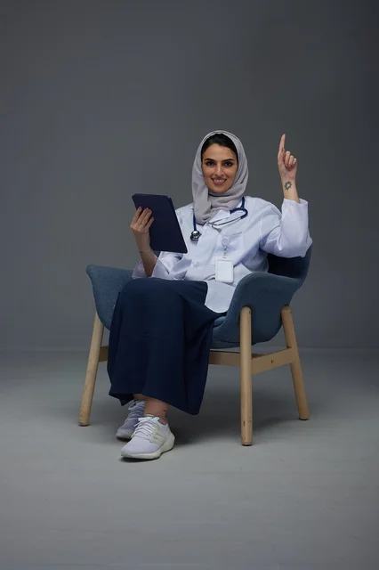 طبيبة سعودية تحمل جهاز لوحي وتشير للأعلى