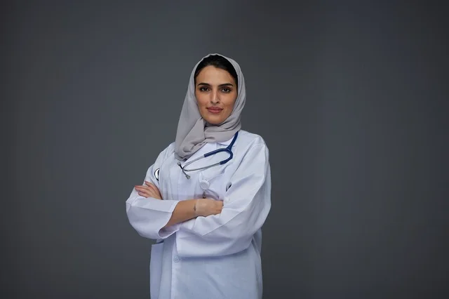 طبيبة سعودية مبتسمة بمعطف طبي أبيض وحجاب