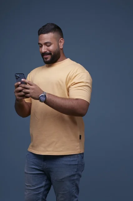 رجل سعودي يستخدم الهاتف الذكي بخلفية زرقاء