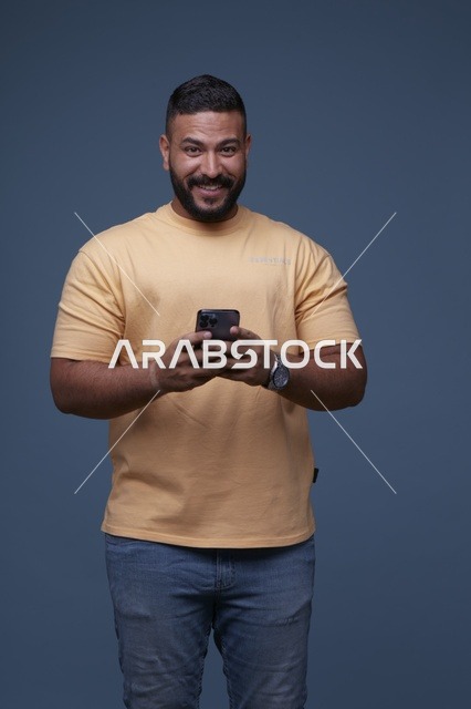 رجل سعودي يستخدم الهاتف الذكي بملابس كاجوال