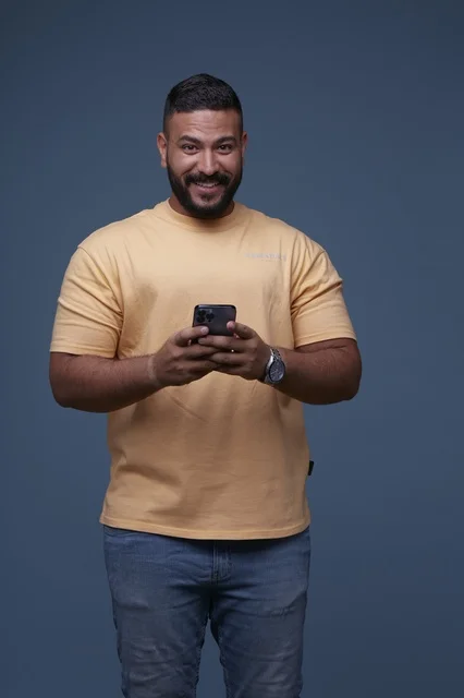 رجل سعودي يستخدم الهاتف الذكي بملابس كاجوال