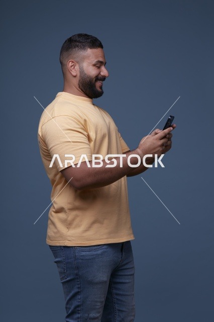 رجل سعودي يستخدم الهاتف الذكي بملابس كاجوال