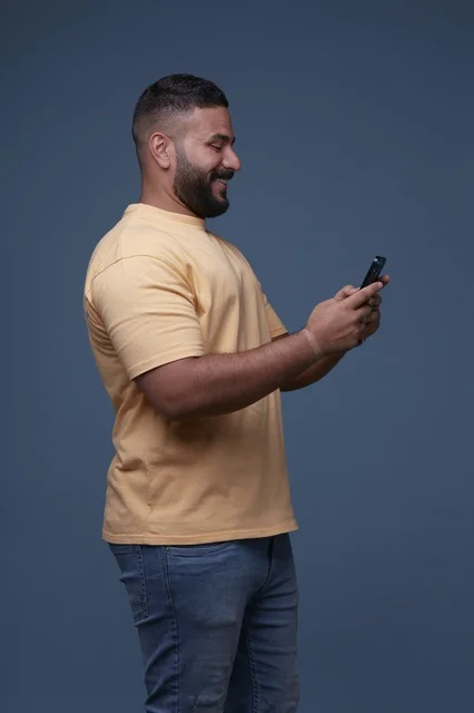 رجل سعودي يستخدم الهاتف الذكي بملابس كاجوال