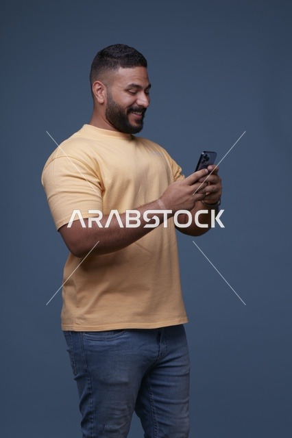 رجل سعودي يستخدم الهاتف الذكي أمام خلفية زرقاء
