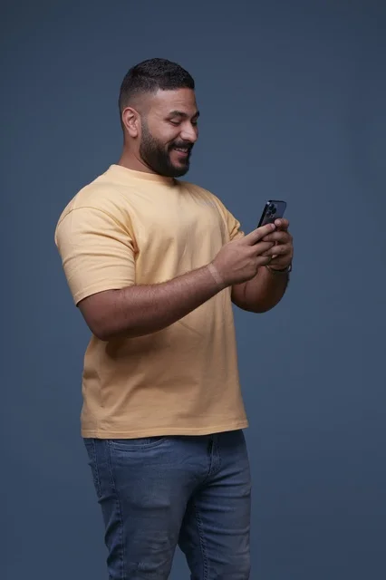 Saudi Man Using Smartphone on Blue Studio Background