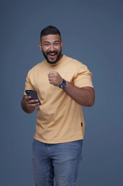 Excited Saudi Man Celebrating Success with Smartphone