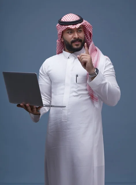 Saudi Man in Traditional Thobe Using Laptop Studio Shot
