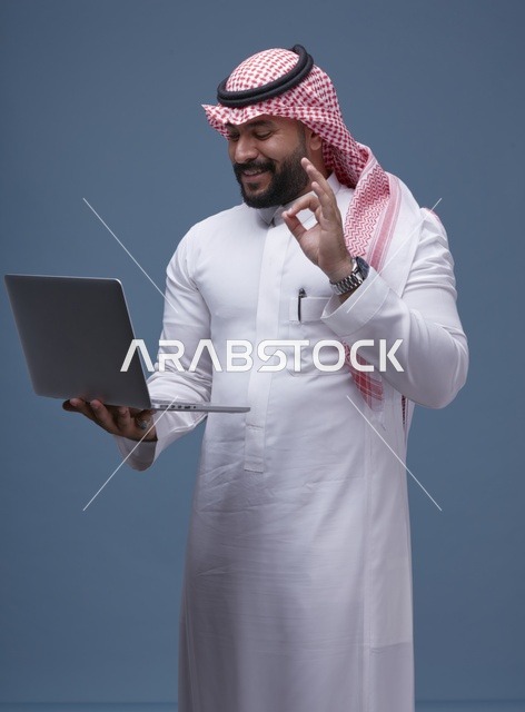رجل سعودي يستخدم الحاسوب المحمول بالزي التقليدي