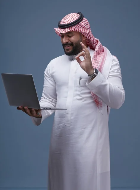 رجل سعودي يستخدم الحاسوب المحمول بالزي التقليدي