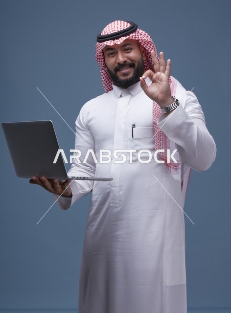 رجل سعودي مع حاسوب محمول وإيماءة التمام