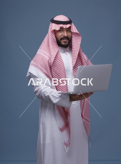 رجل سعودي مع حاسوب محمول بالزي السعودي التقليدي