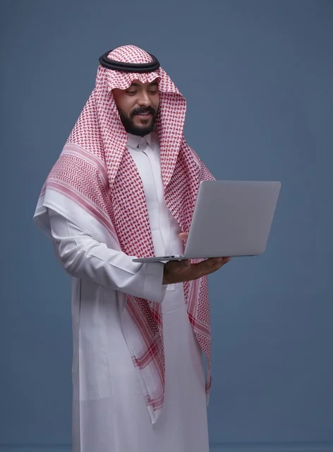 رجل سعودي مع حاسوب محمول بالزي التقليدي في استوديو