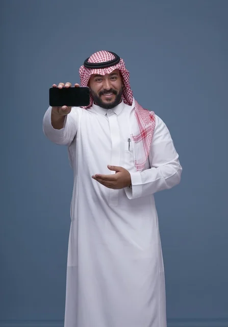 رجل سعودي يحمل هاتف ذكي بشاشة فارغة بالزي التقليدي