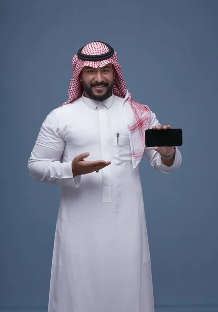 رجل سعودي يحمل هاتف ذكي بشاشة فارغة بالزي التقليدي
