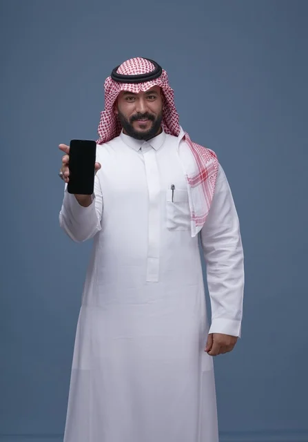 رجل سعودي يحمل هاتفاً بشاشة فارغة في الاستوديو