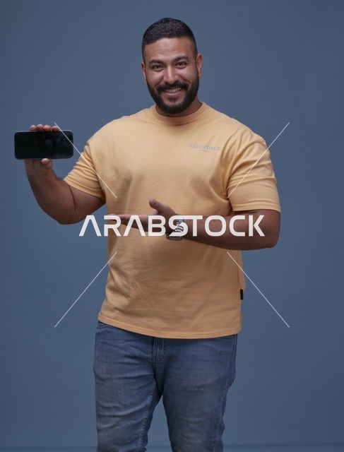 رجل سعودي مبتسم يحمل هاتف بشاشة فارغة