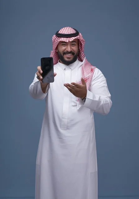 رجل سعودي يحمل هاتف ذكي بشاشة فارغة في استوديو