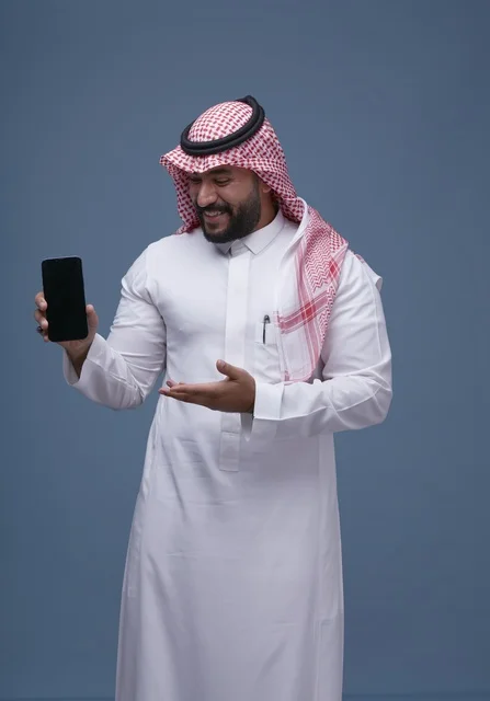 رجل سعودي بالزي التقليدي يحمل هاتفاً بشاشة فارغة