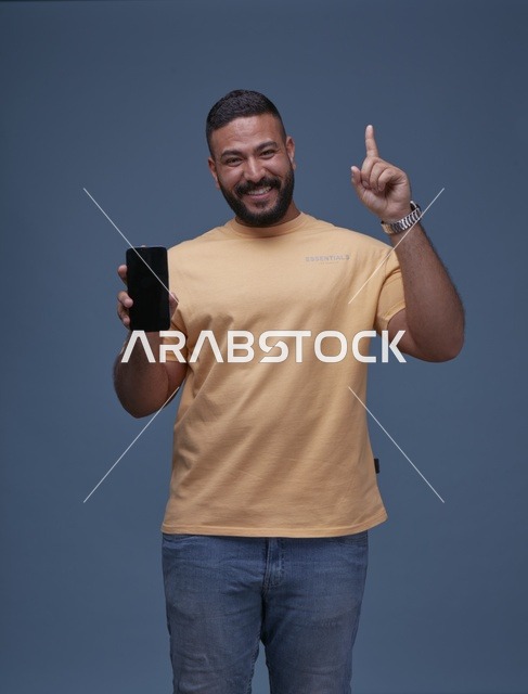 رجل سعودي مبتسم يمسك هاتف بشاشة فارغة