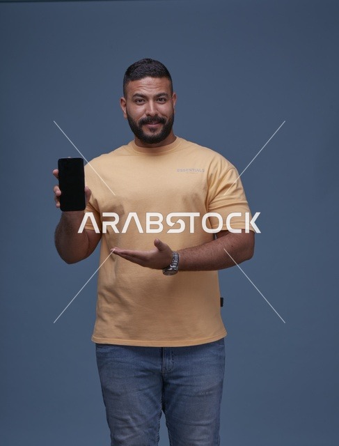 رجل سعودي يحمل هاتفاً ذكياً بشاشة فارغة