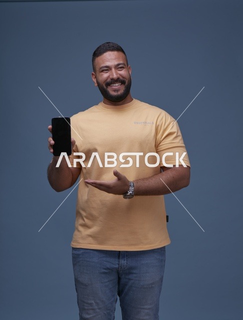 رجل سعودي مبتسم يمسك هاتف ذكي بشاشة فارغة للإعلان