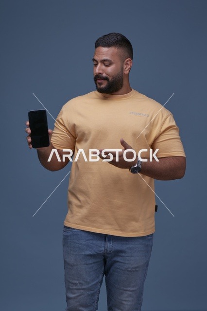 رجل سعودي يعرض شاشة جوال فارغة بملابس كاجوال