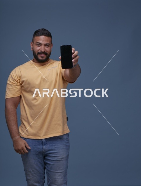 رجل سعودي يحمل هاتف ذكي بشاشة فارغة بملابس كاجوال