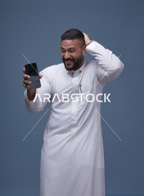 رجل سعودي بالثوب الأبيض مندهش من شاشة الجوال