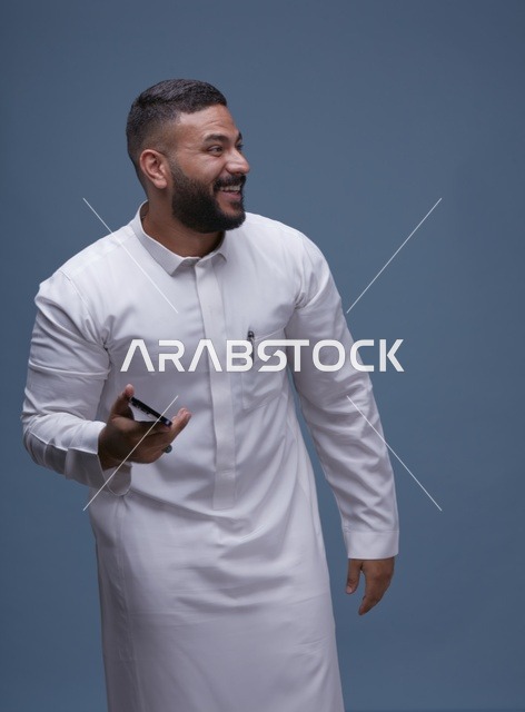 رجل سعودي بالثوب الأبيض يحمل هاتف ذكي