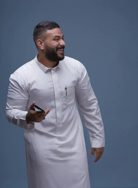 رجل سعودي بالثوب الأبيض يحمل هاتف ذكي