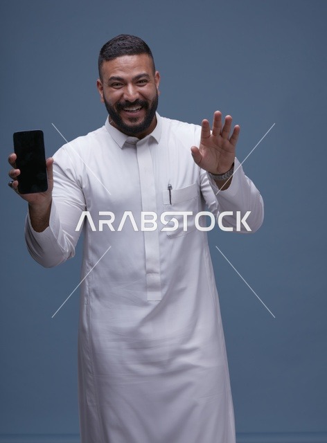 رجل سعودي يمسك هاتف بشاشة فارغة في الاستوديو