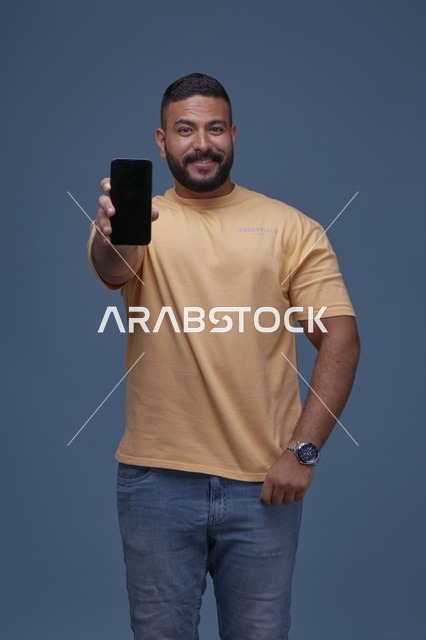رجل سعودي يحمل هاتف بشاشة فارغة في الاستوديو
