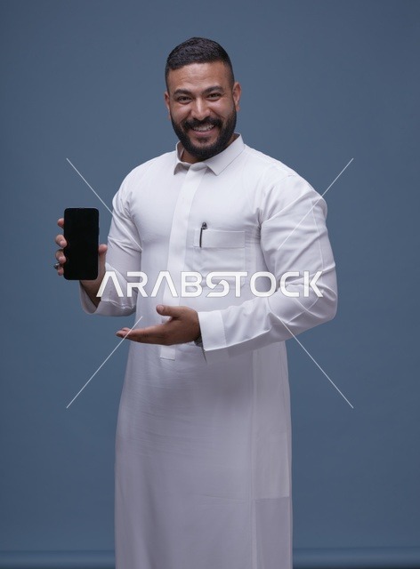 رجل سعودي بالثوب الأبيض يحمل هاتف ذكي فارغ