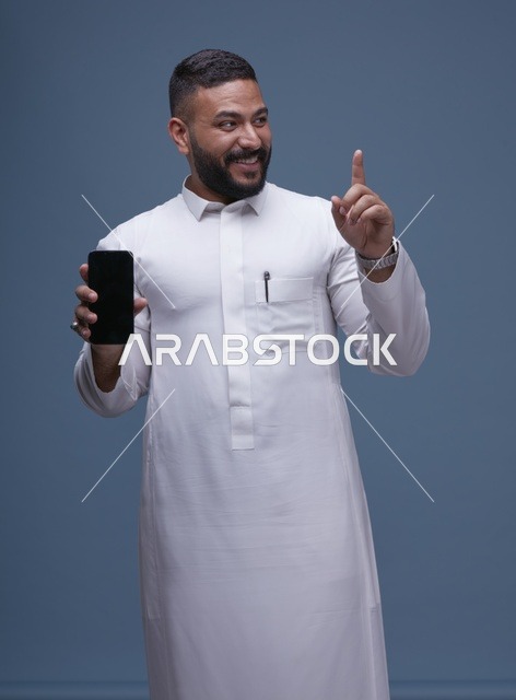 رجل سعودي بالثوب الأبيض يحمل هاتفاً بشاشة فارغة