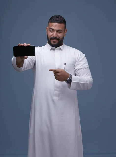 Saudi Man in White Thobe Pointing at Blank Phone Screen