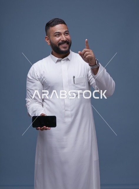 رجل سعودي بالثوب الأبيض يمسك هاتف بشاشة فارغة