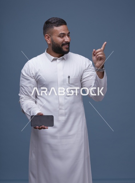 رجل سعودي بالثوب الأبيض يحمل هاتف بشاشة فارغة