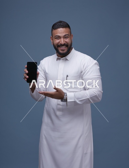 رجل سعودي بالثوب الأبيض يمسك هاتف بشاشة فارغة