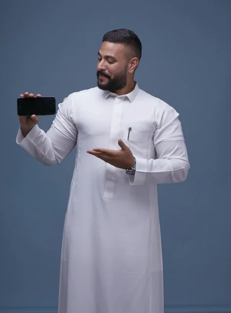 Saudi Man in White Thobe Displaying Empty Smartphone