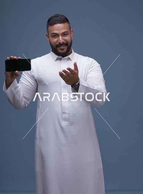 رجل سعودي يمسك هاتف بشاشة فارغة بالثوب الأبيض