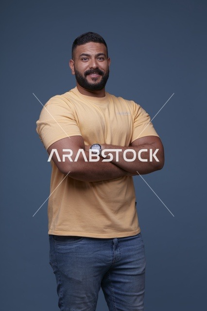 بورتريه رجل سعودي مبتسم بتيشيرت أصفر كاجوال بخلفية زرقاء