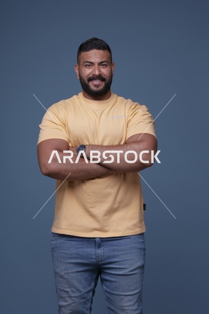بورتريه لرجل سعودي مبتسم بتيشيرت أصفر خلفية زرقاء