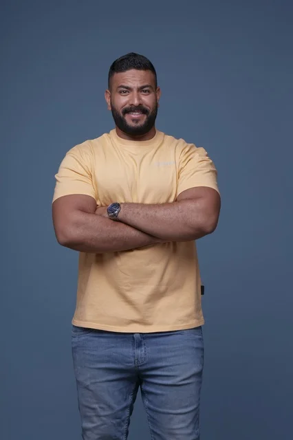 بورتريه لرجل سعودي مبتسم بتيشيرت أصفر خلفية زرقاء