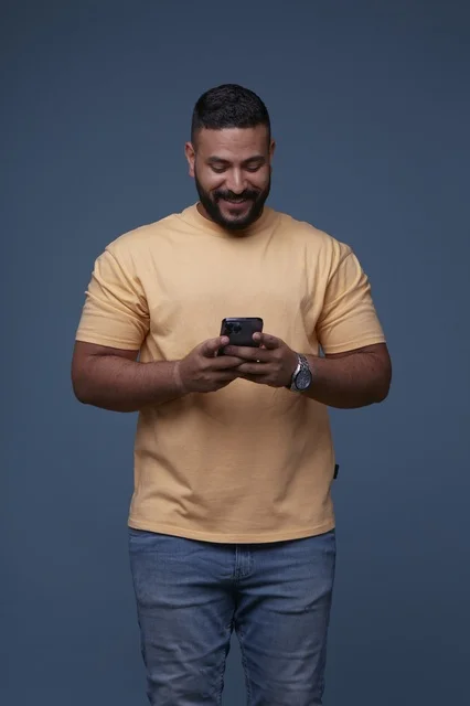 Saudi Man in Casual Clothes Typing on Smartphone Studio