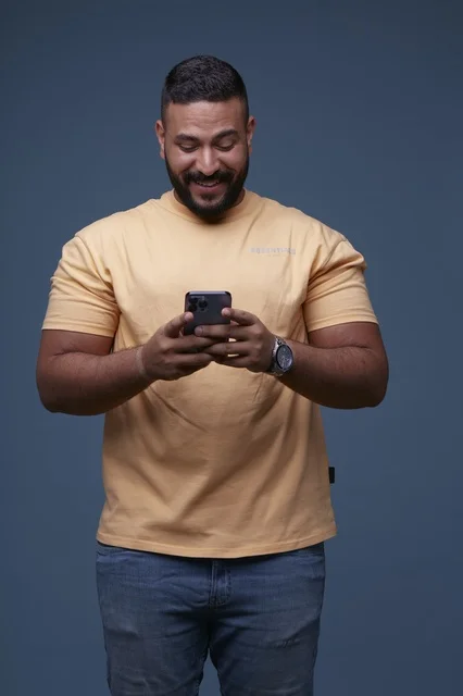 رجل سعودي يستخدم الهاتف الذكي بملابس كاجوال في الاستوديو