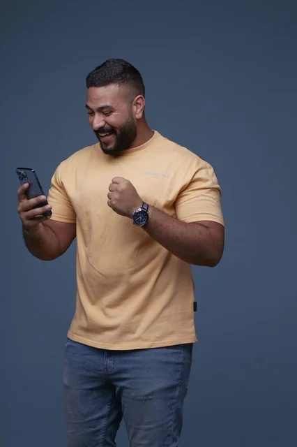Saudi Man Celebrating Success with Smartphone in Studio