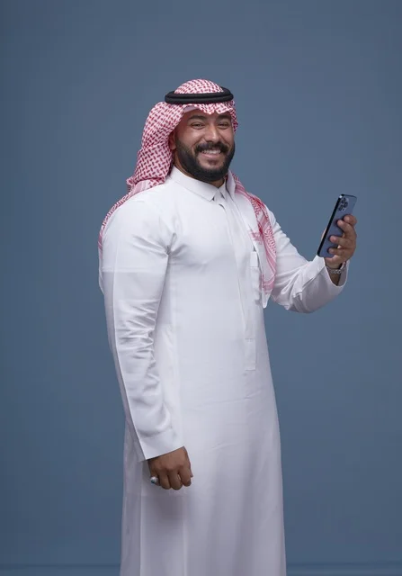 Smiling Saudi Man Using Smartphone in Traditional Attire