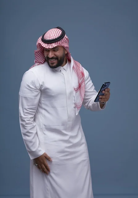 Saudi Man in Traditional Thobe Using Smartphone Studio