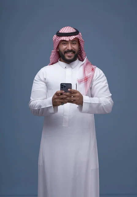 Smiling Saudi Man Using Smartphone in Traditional Dress