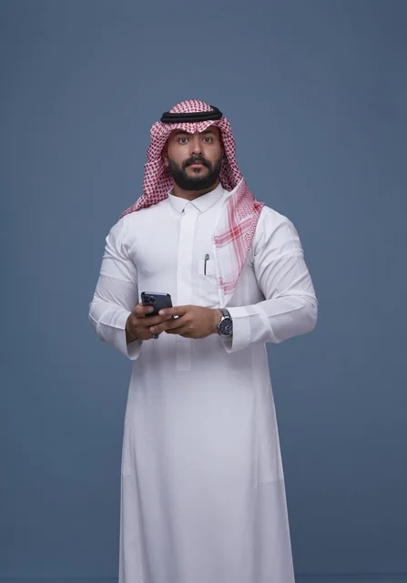 Saudi Man in Traditional Thobe Holding Smartphone Studio